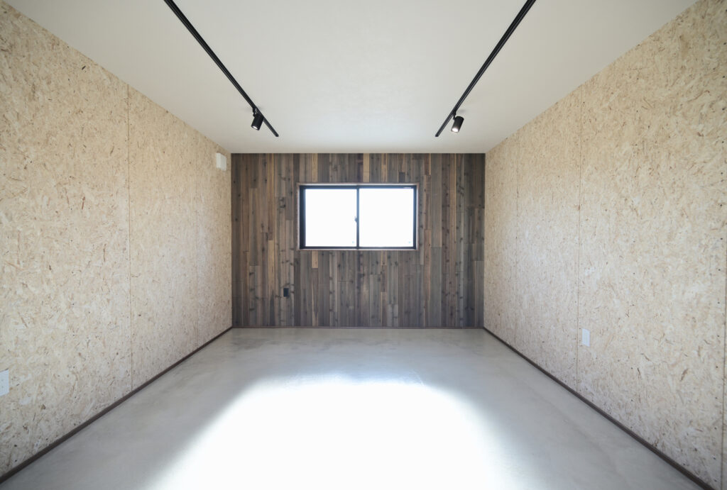 エコーアートが建てた青と質感にこだわったドーマーのあるかわいい家の横のかっこいいガレージの板張りエイジング塗装