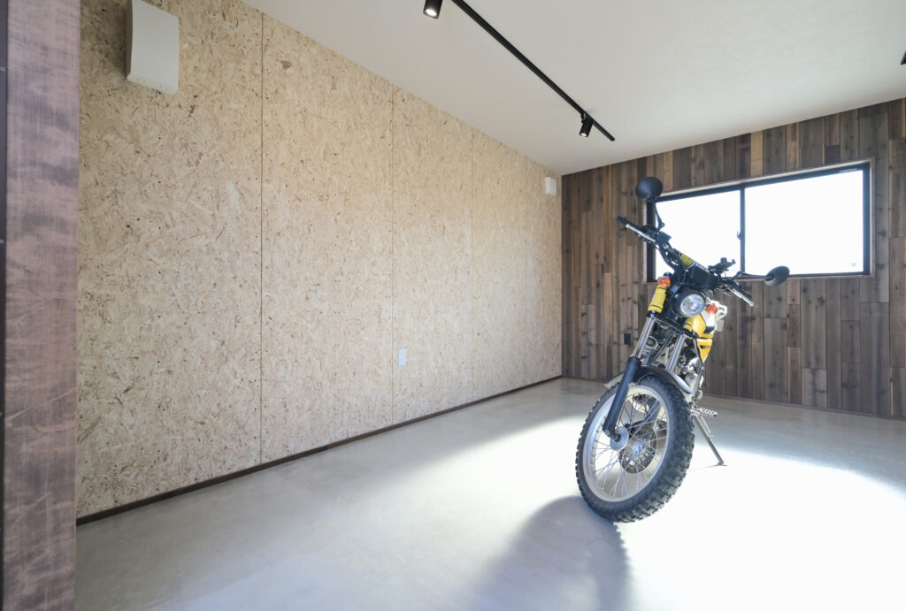 エコーアートが建てた青と質感にこだわったドーマーのあるかわいい家の横のかっこいいガレージの板張りエイジング塗装