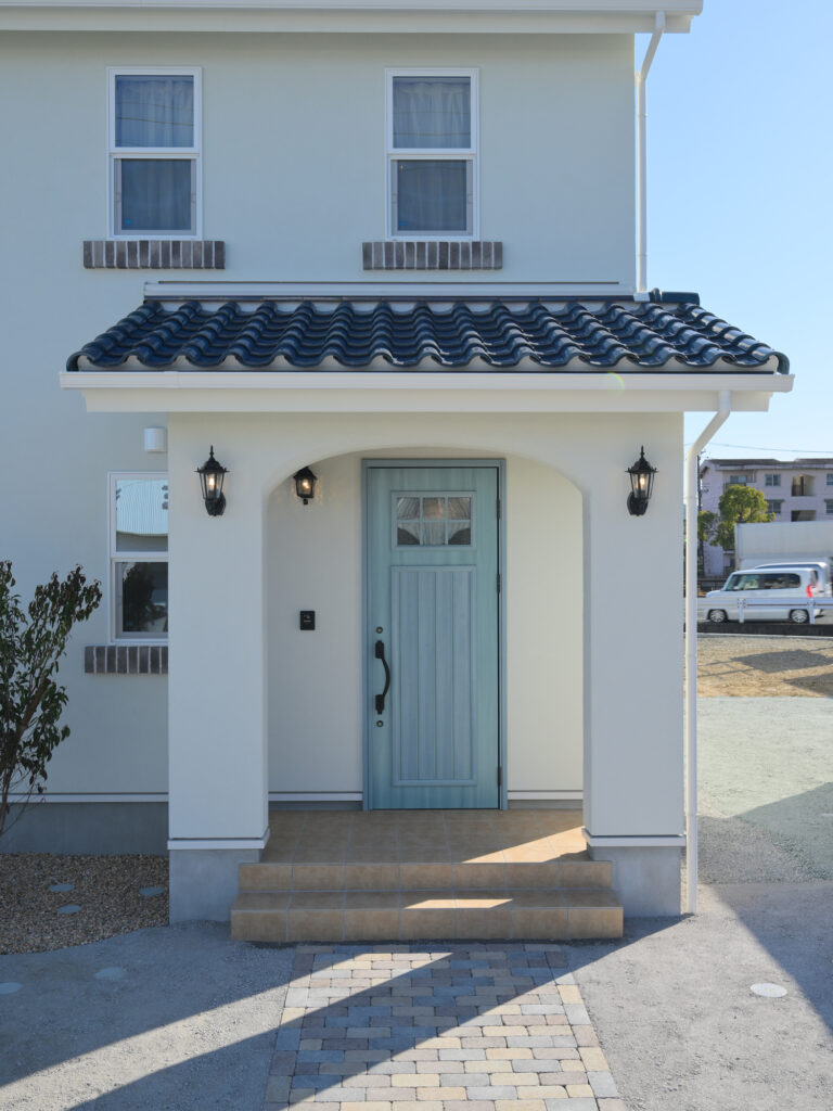 エコーアートが建てた青と質感にこだわったドーマーのあるかわいい家の玄関下屋アーチ壁写真